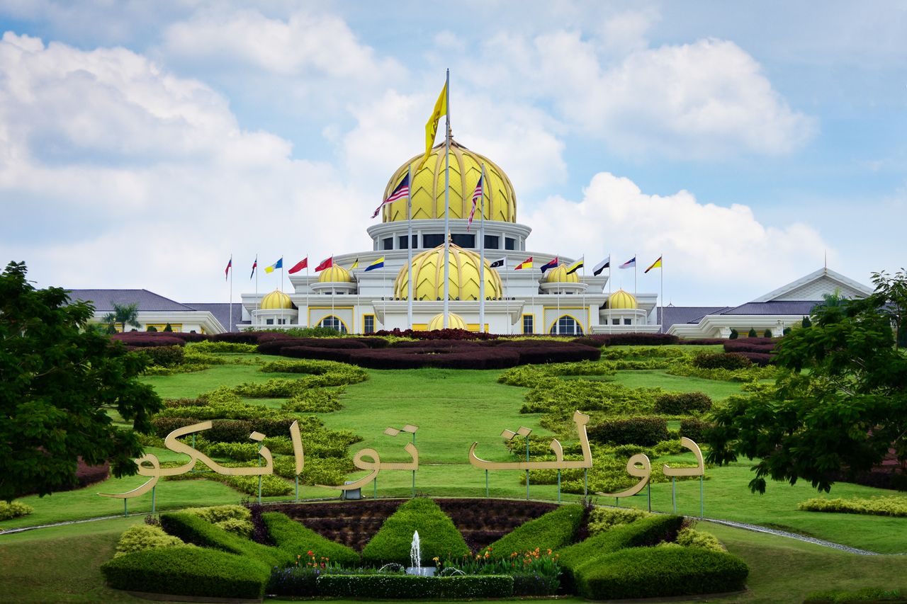 View of the Istana Negara Palace in Kuala Lumpur with lush gardens and clear blue sky.